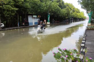Pengendara motor melintasi banjir