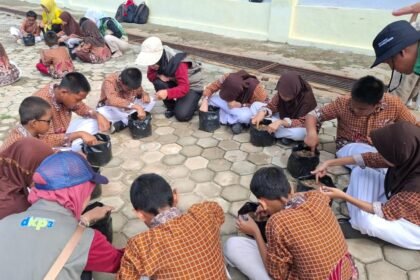 Para pelajar SDN 009 Bontang Utara menanam bibit kangkung di launching smartani Goes To School. (istimewa)